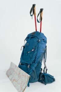 Blue backpack with trekking poles and map, ready for an adventure.