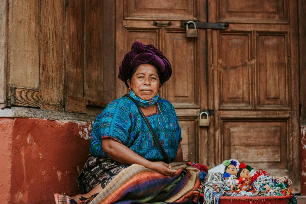 Traditional Guatemalan woman selling handmade crafts in Antigua. Vibrant textiles and dolls, cultural heritage.